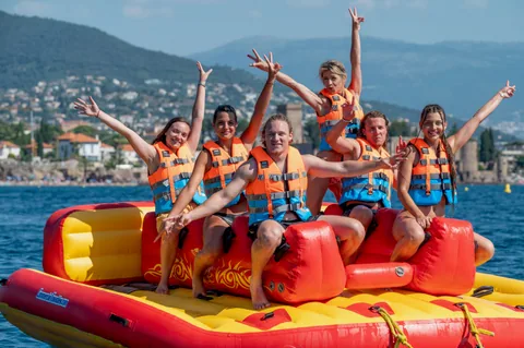 Bouée tractée à Mandelieu : groupe d'amis bras levés dans le golfe de la Napoule, près de Cannes